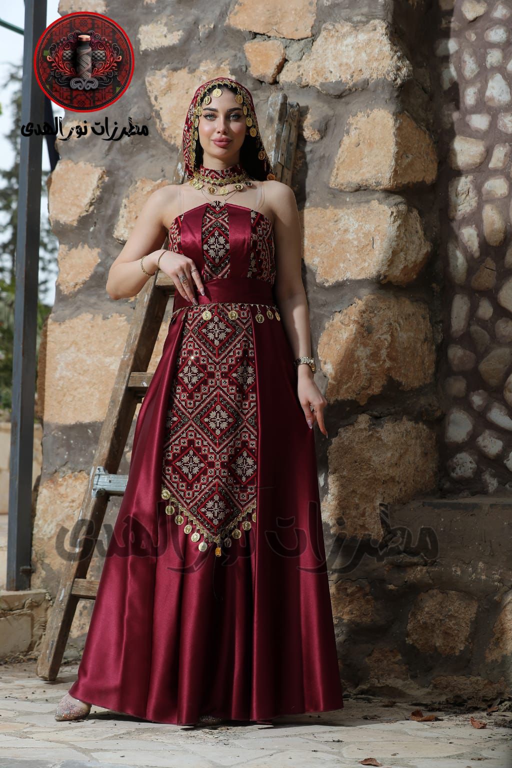 Close front view of burgundy Palestinian embroidered henna dress with coin details and matching draped accessory