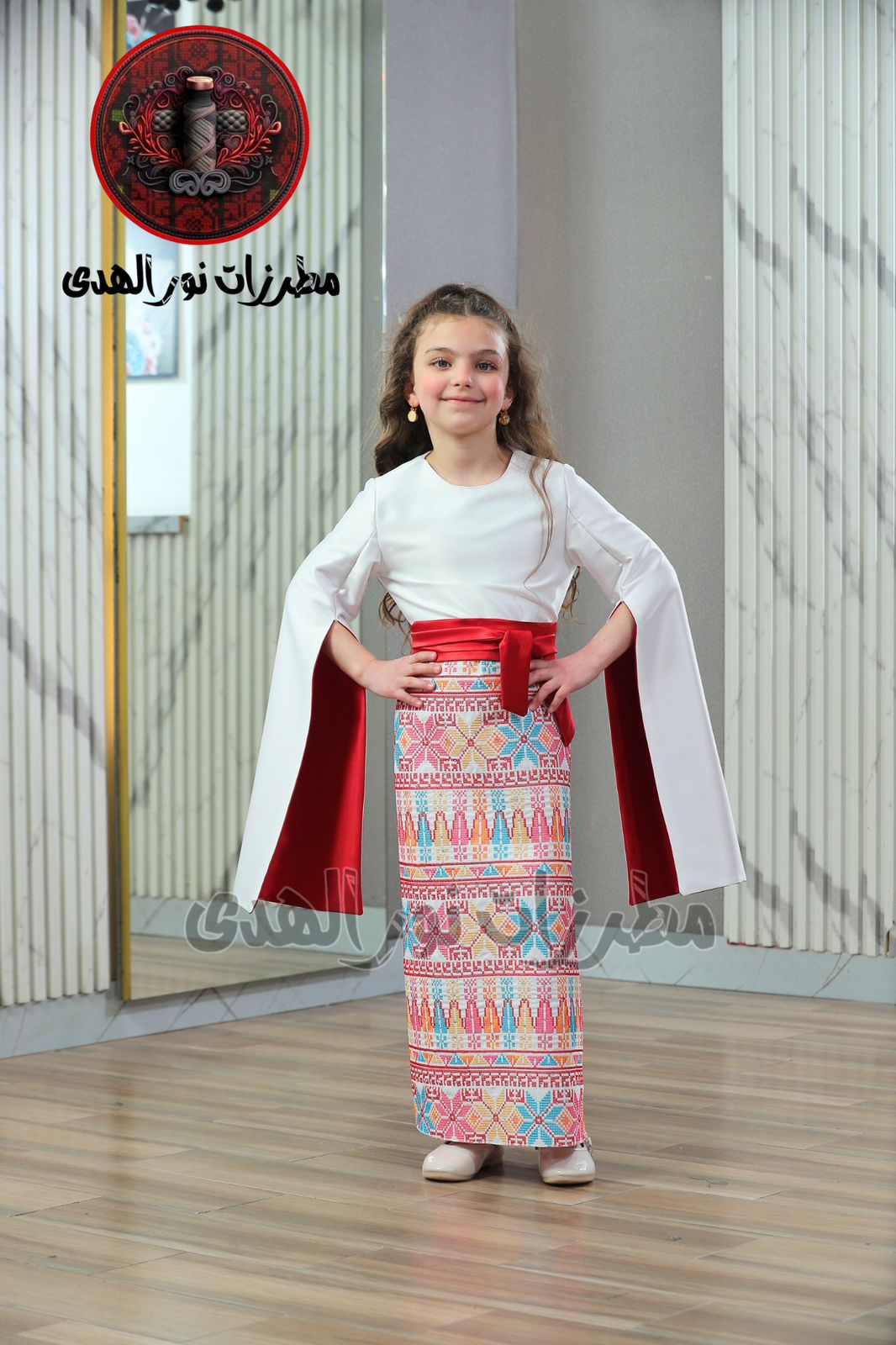 White girls Palestinian embroidered satin heritage dress with red sash, split sleeves, and red Tatreez-inspired skirt panel