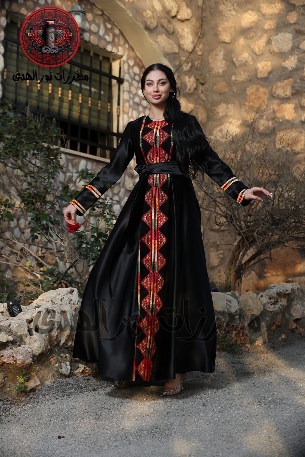 Black satin Palestinian embroidered thobe with colorful Tatreez-inspired front panel, long sleeves, and black satin belt, ثوب فلسطيني مطرز باللون الأسود من قماش الستان مع تطريز ملون مستوحى من التطريز الفلسطيني وحزام ستان أسود