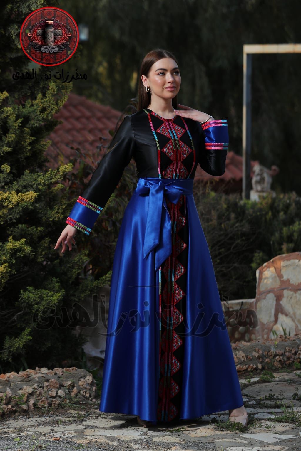 Black satin Palestinian embroidered thobe with colorful Tatreez-inspired front panel, long sleeves, and black satin belt, ثوب فلسطيني مطرز باللون الأسود من قماش الستان مع تطريز ملون مستوحى من التطريز الفلسطيني وحزام ستان أسود
