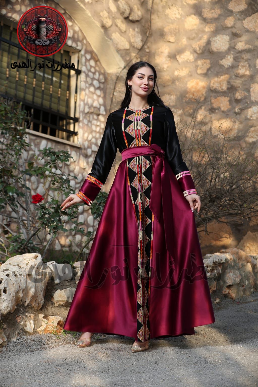 Black satin Palestinian embroidered thobe with colorful Tatreez-inspired front panel, long sleeves, and black satin belt, ثوب فلسطيني مطرز باللون الأسود من قماش الستان مع تطريز ملون مستوحى من التطريز الفلسطيني وحزام ستان أسود