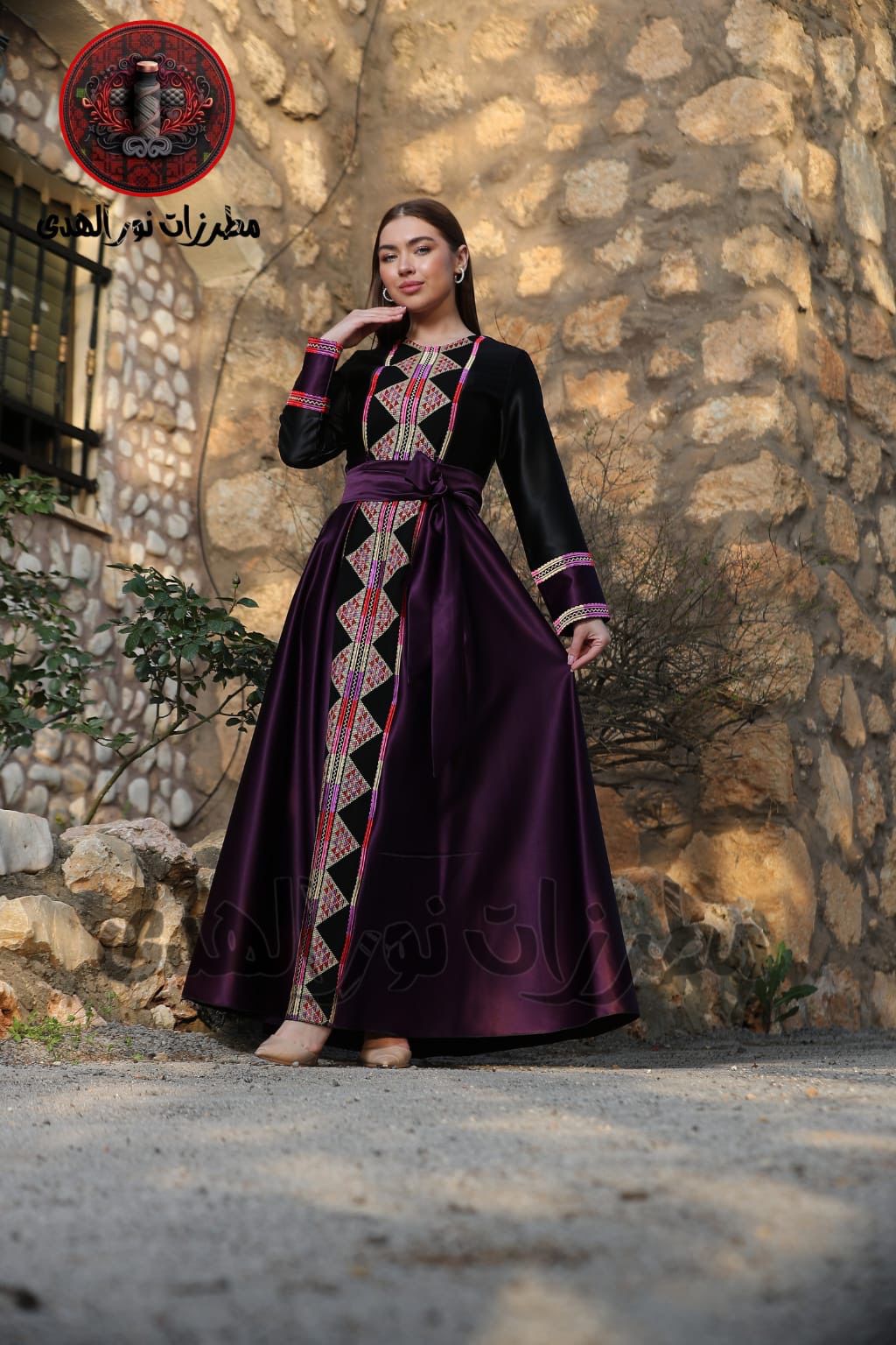 Black satin Palestinian embroidered thobe with colorful Tatreez-inspired front panel, long sleeves, and black satin belt, ثوب فلسطيني مطرز باللون الأسود من قماش الستان مع تطريز ملون مستوحى من التطريز الفلسطيني وحزام ستان أسود