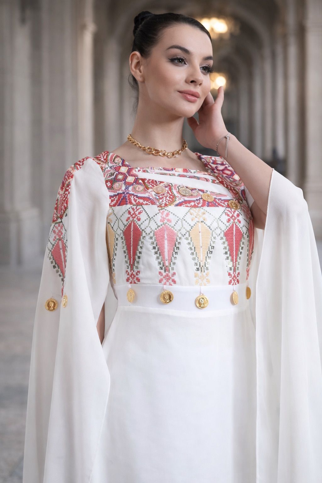 White chiffon lined Palestinian embroidered thobe with square neckline, gold coin details, and flowing cape-style sleeves, ثوب فلسطيني أبيض من الشيفون المبطن مع فتحة رقبة مربعة وتطريز ملون وتفاصيل عملات ذهبية وأكمام كاب منسدلة