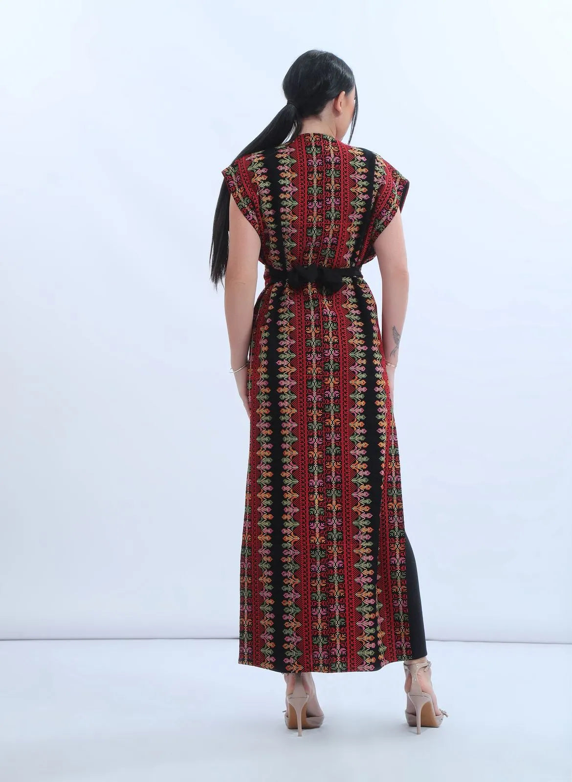 Model wearing a fully embroidered sleeveless Levantine bisht in black chiffon with red and multicolor Tatreez-inspired embroidery, عارضة ترتدي بشت نسائي شامي مطرز بالكامل من الشيفون الأسود بتطريز تراثي متعدد الألوان.