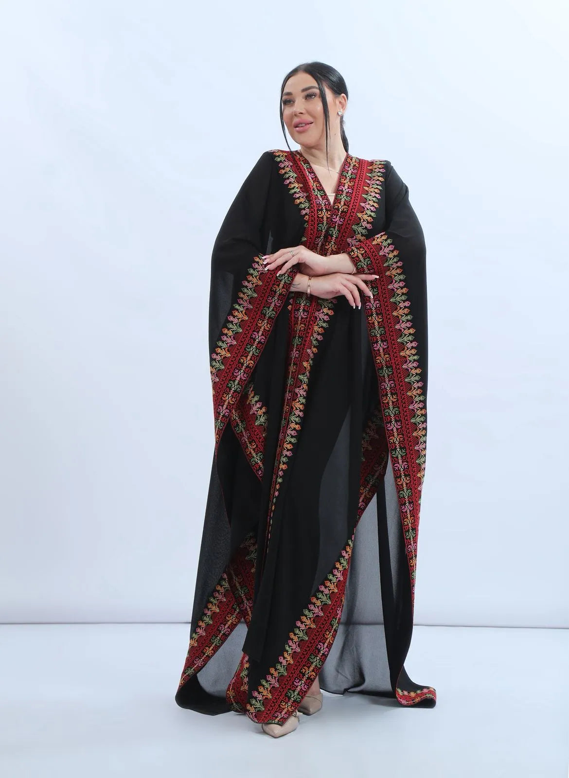 Front view of the black chiffon Khaleeji bisht worn closed with a V-neckline and embroidered bands falling from shoulder to hem, منظر أمامي للبشت الخليجي الأسود من الشيفون بفتحة رقبة على شكل V وأشرطة تطريز تمتد من الكتف حتى الأسفل
