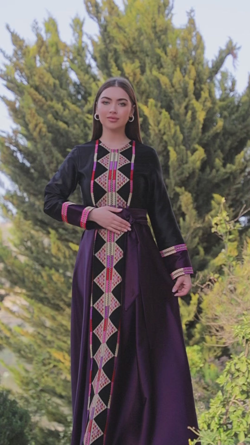 Black satin Palestinian embroidered thobe with colorful Tatreez-inspired front panel, long sleeves, and black satin belt, ثوب فلسطيني مطرز باللون الأسود من قماش الستان مع تطريز ملون مستوحى من التطريز الفلسطيني وحزام ستان أسود