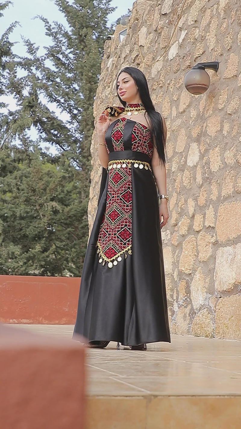 Black Palestinian embroidered henna dress with red Tatreez-inspired details, gold coin accents, and elegant heritage styling